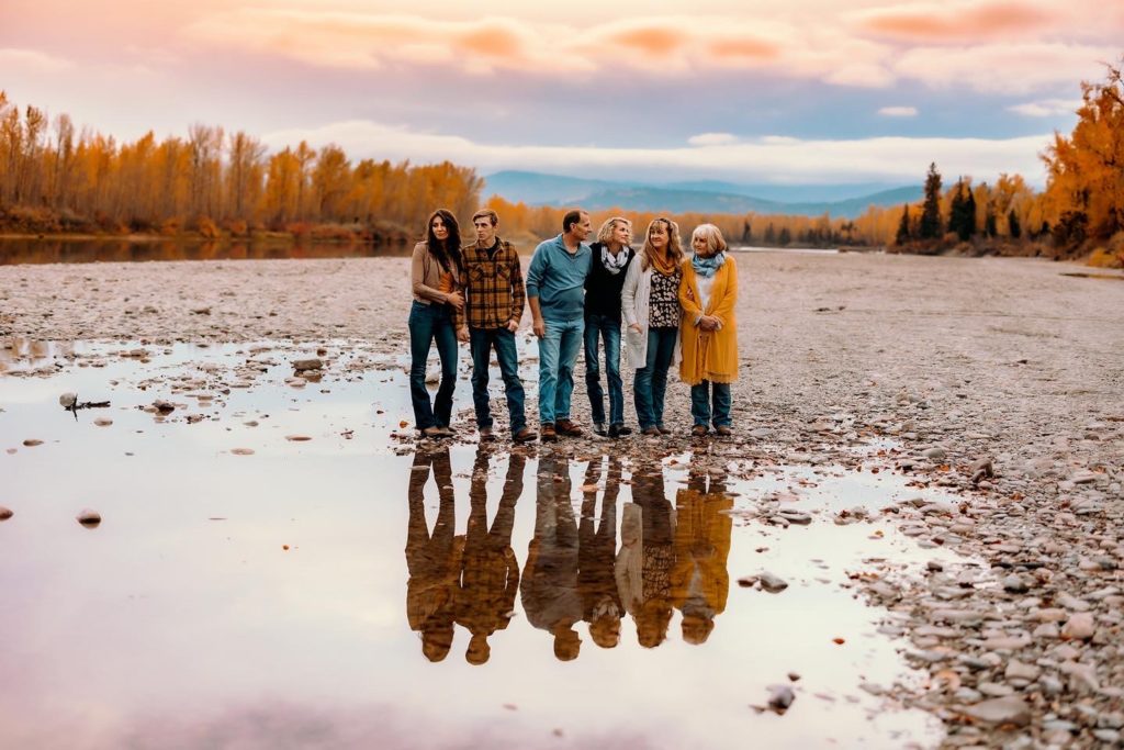 extended family standing in front of the sunset with their reflection in the water